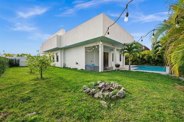 rear view of house featuring a fenced in pool, a lawn, and a patio