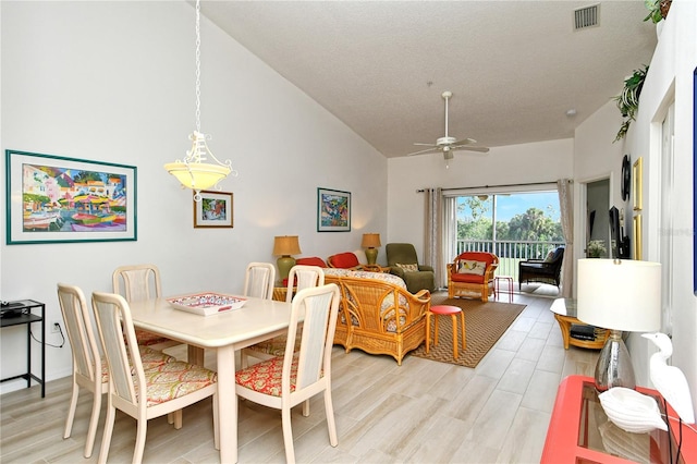 dining area featuring ceiling fan, high vaulted ceiling, and light hardwood / wood-style flooring