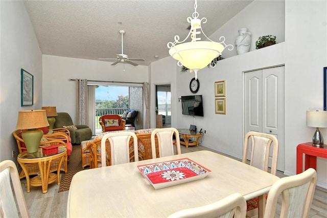 dining space with ceiling fan, lofted ceiling, light hardwood / wood-style floors, and a textured ceiling