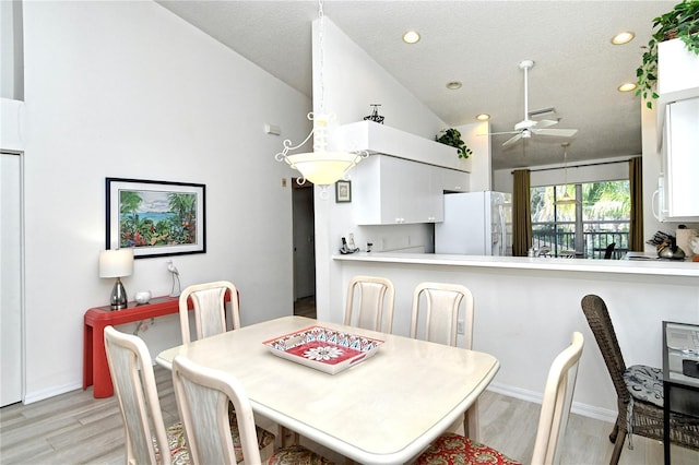 dining room featuring ceiling fan, light hardwood / wood-style floors, vaulted ceiling, and a textured ceiling