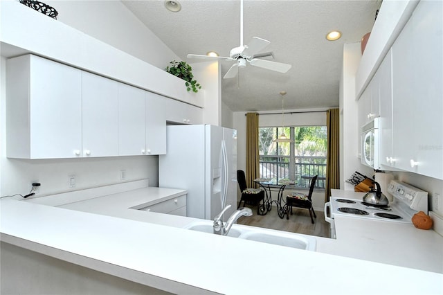 kitchen featuring vaulted ceiling, white cabinetry, sink, white appliances, and a textured ceiling