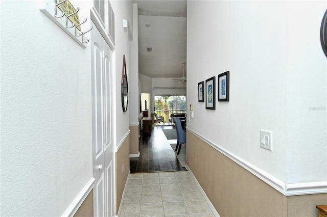 hallway featuring a towering ceiling and light tile patterned floors