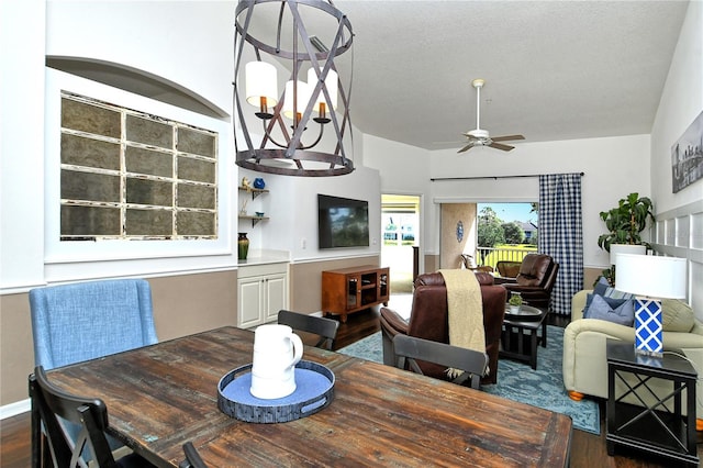 dining room featuring dark hardwood / wood-style flooring, ceiling fan with notable chandelier, and a textured ceiling