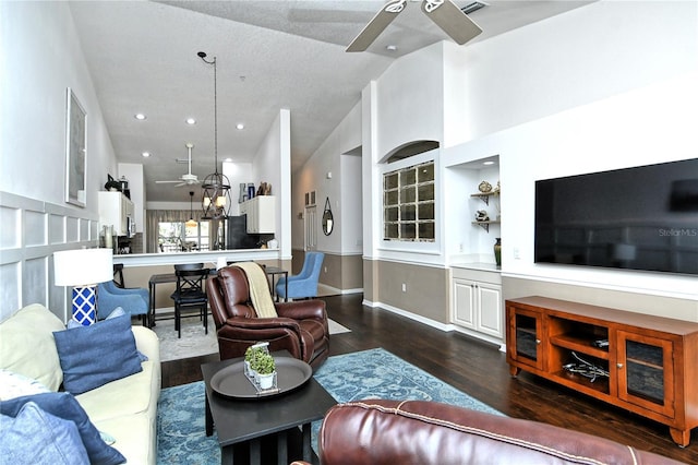 living room with high vaulted ceiling, dark wood-type flooring, ceiling fan, and built in shelves