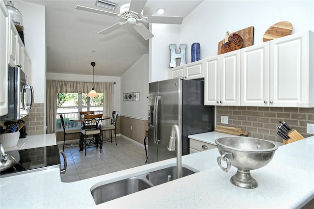 kitchen with sink, appliances with stainless steel finishes, white cabinetry, tasteful backsplash, and decorative light fixtures