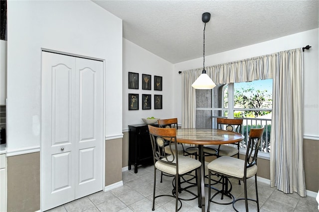 tiled dining space with vaulted ceiling and a textured ceiling