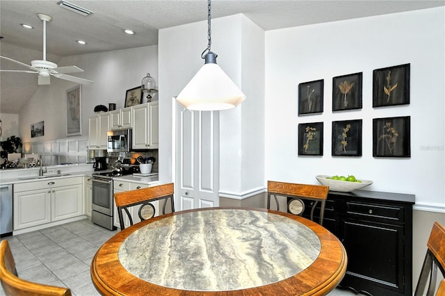 dining room featuring light tile patterned flooring, lofted ceiling, sink, and ceiling fan