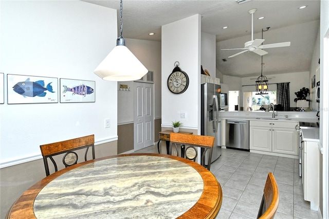 tiled dining space featuring vaulted ceiling, sink, and ceiling fan