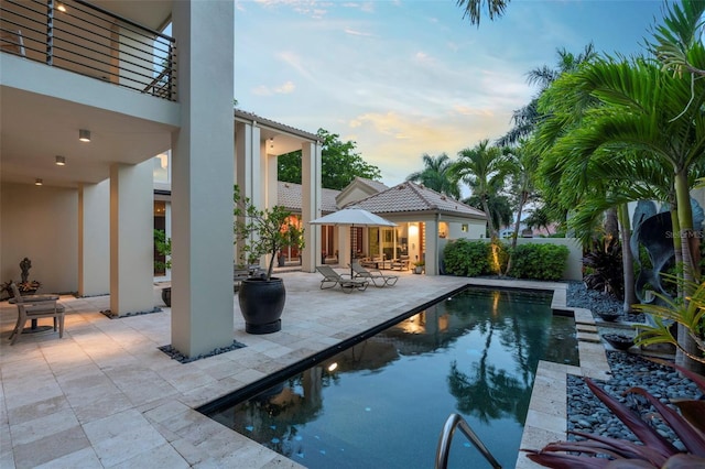 pool at dusk featuring a patio area