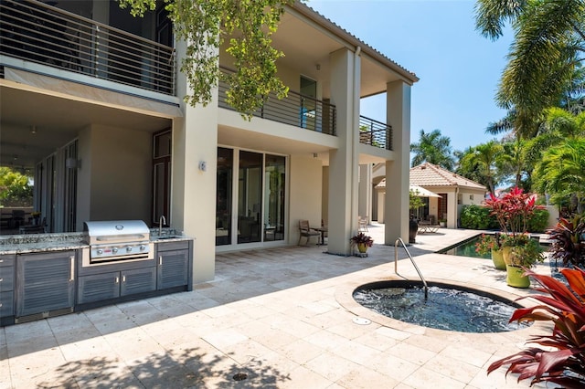 rear view of house featuring sink, a patio, a pool with hot tub, area for grilling, and a balcony