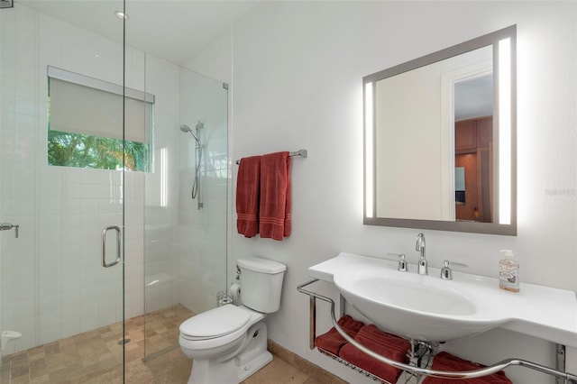 bathroom featuring sink, toilet, and a shower with door