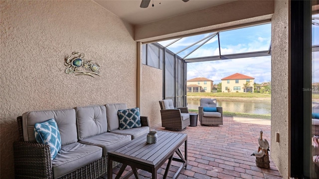 view of patio / terrace featuring ceiling fan, a water view, outdoor lounge area, and glass enclosure