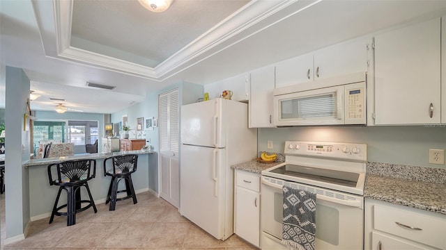 kitchen featuring a raised ceiling, white cabinetry, crown molding, and white appliances