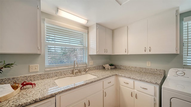 washroom with sink, washer / dryer, and cabinets