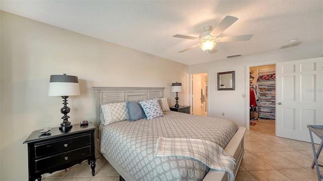 tiled bedroom featuring ceiling fan, a spacious closet, a closet, and a textured ceiling