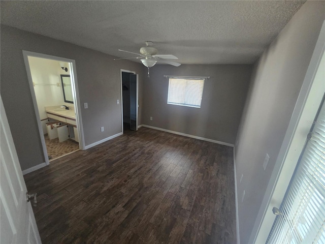 unfurnished bedroom with connected bathroom, dark hardwood / wood-style floors, a textured ceiling, and ceiling fan