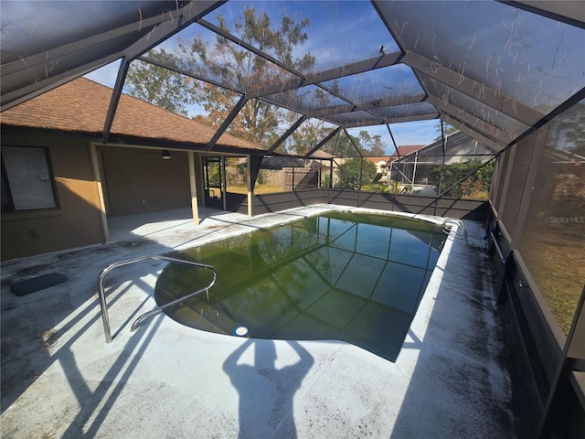 view of swimming pool featuring glass enclosure and a patio area