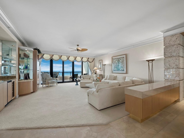 living room featuring beverage cooler, a wall of windows, light colored carpet, ceiling fan, and a water view