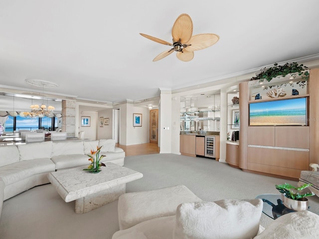 living room with wine cooler, light colored carpet, ornamental molding, and ceiling fan with notable chandelier