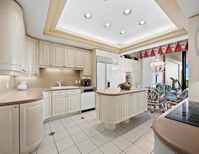 kitchen featuring sink, paneled built in fridge, a raised ceiling, and dishwasher