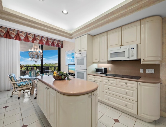 kitchen featuring a center island, light tile patterned floors, a notable chandelier, white appliances, and cream cabinets