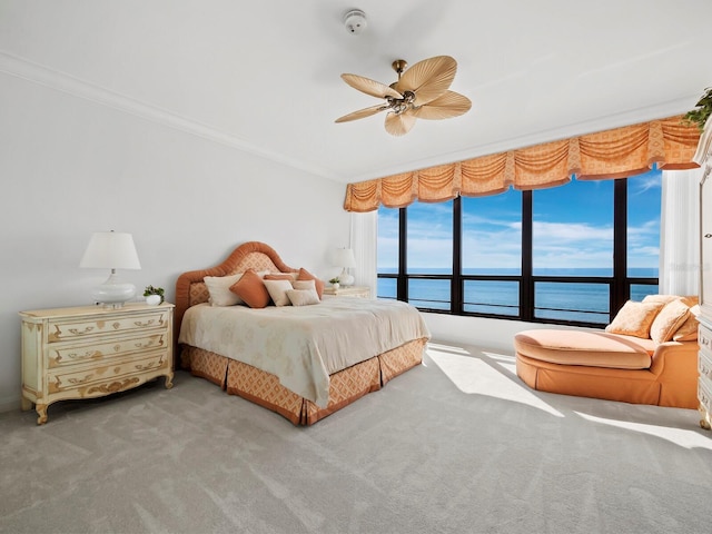 carpeted bedroom with a water view, ceiling fan, and crown molding