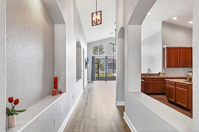 corridor with hardwood / wood-style floors, high vaulted ceiling, and sink