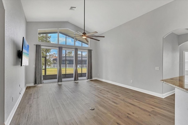 unfurnished living room featuring wood-type flooring, high vaulted ceiling, and ceiling fan