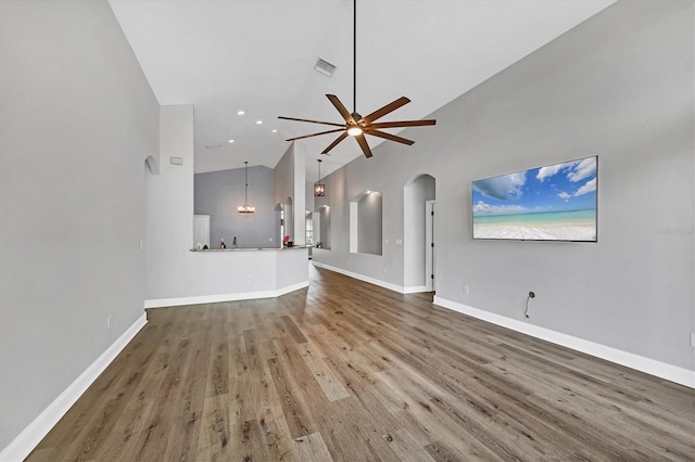 unfurnished living room with wood-type flooring, high vaulted ceiling, and ceiling fan