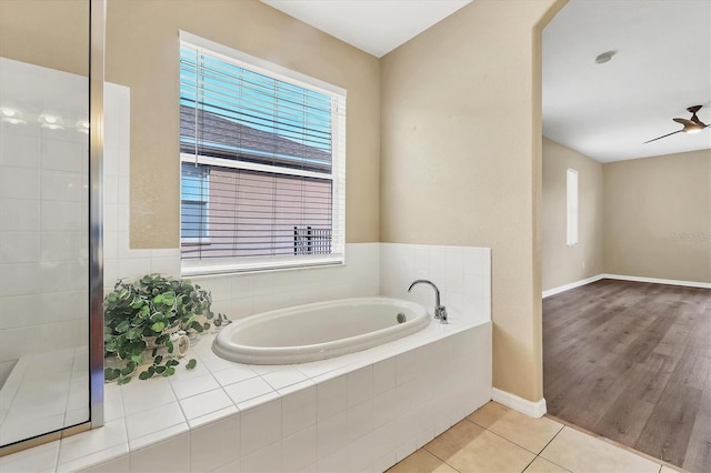 bathroom featuring a relaxing tiled tub, ceiling fan, and tile patterned floors