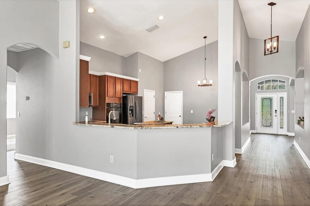 kitchen with dark hardwood / wood-style floors, decorative light fixtures, stainless steel fridge, kitchen peninsula, and an inviting chandelier