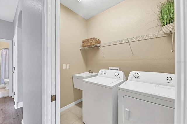 washroom with sink, light tile patterned floors, and washer and clothes dryer