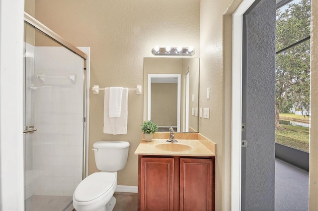 bathroom featuring a shower with door, vanity, and toilet