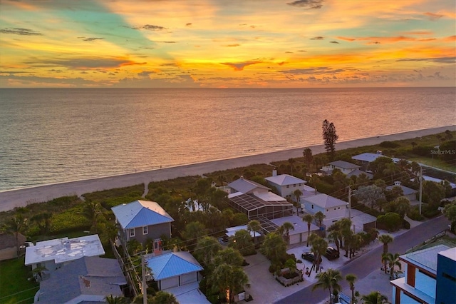 aerial view at dusk with a view of the beach and a water view