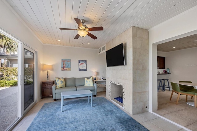 living room featuring a tiled fireplace, crown molding, light tile patterned floors, and wood ceiling