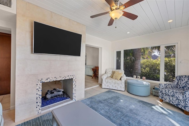 living room with light tile patterned flooring, ceiling fan, wooden ceiling, and a fireplace