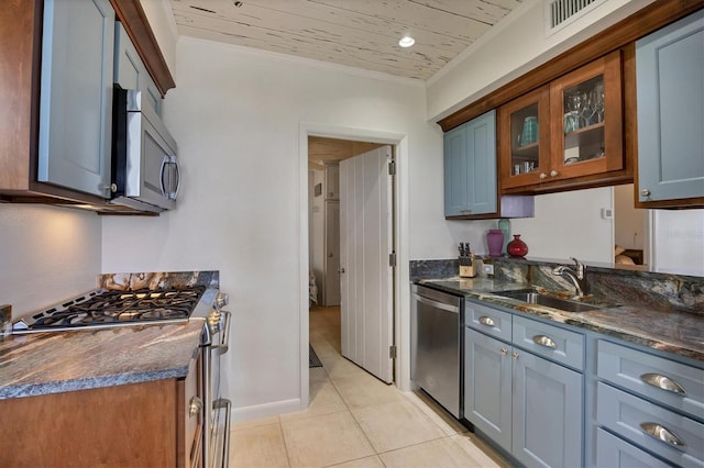 kitchen with stainless steel appliances, ornamental molding, sink, and dark stone counters