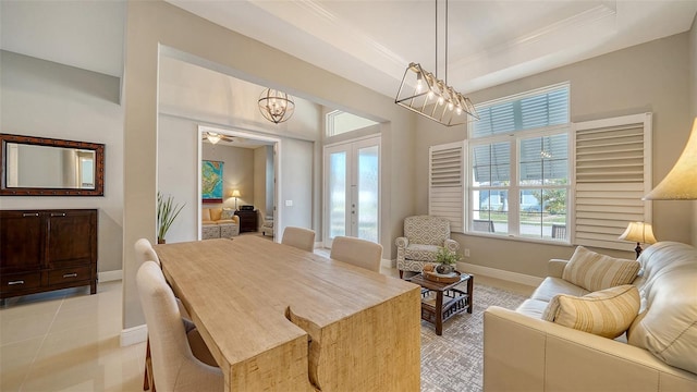 dining area with light tile patterned floors, a notable chandelier, a raised ceiling, crown molding, and french doors