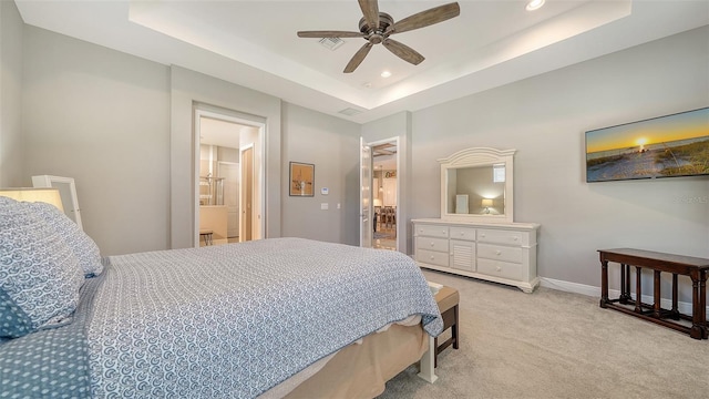 carpeted bedroom featuring a raised ceiling, ensuite bathroom, and ceiling fan