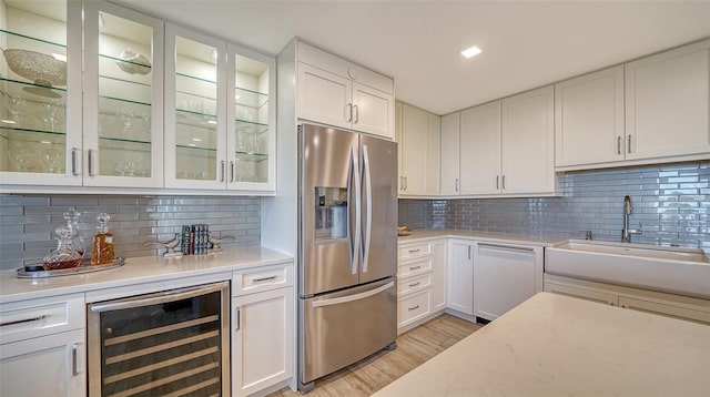 kitchen with stainless steel refrigerator with ice dispenser, sink, white cabinetry, white dishwasher, and beverage cooler