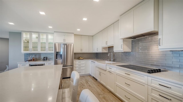 kitchen with sink, white cabinets, stainless steel fridge, black electric stovetop, and light hardwood / wood-style flooring