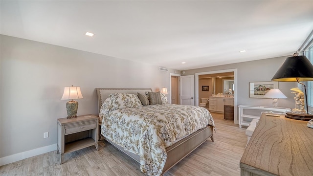 bedroom with light wood-type flooring and ensuite bath