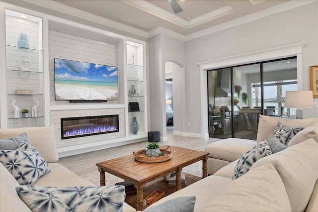 living room featuring crown molding, light wood-type flooring, and built in shelves