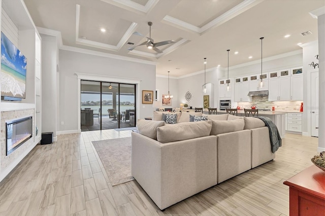 living room with crown molding, a fireplace, and a high ceiling