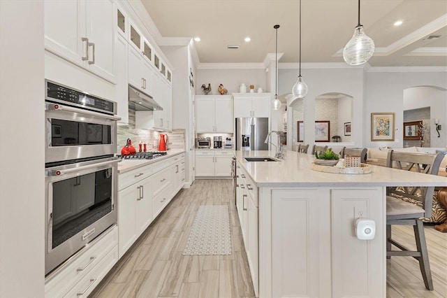 kitchen featuring sink, decorative light fixtures, a kitchen breakfast bar, a kitchen island with sink, and white cabinets