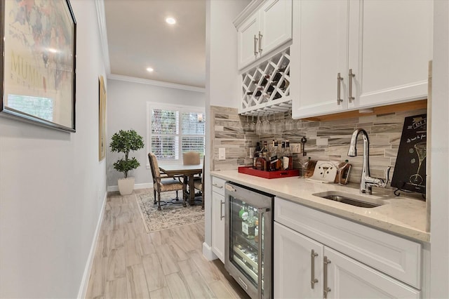 bar with sink, white cabinetry, ornamental molding, decorative backsplash, and beverage cooler