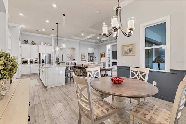 dining room featuring beamed ceiling, coffered ceiling, crown molding, an inviting chandelier, and light hardwood / wood-style flooring