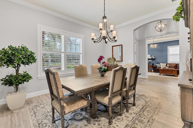 dining area with crown molding, plenty of natural light, light wood-type flooring, and a notable chandelier