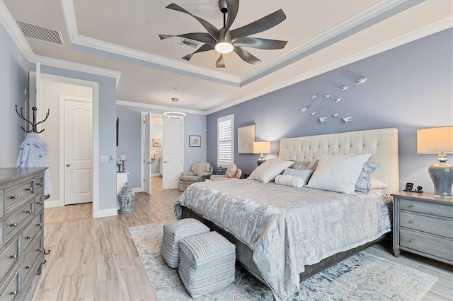 bedroom featuring a tray ceiling, light hardwood / wood-style flooring, ornamental molding, and ceiling fan