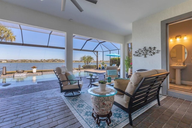 view of patio with a water view, ceiling fan, and a lanai